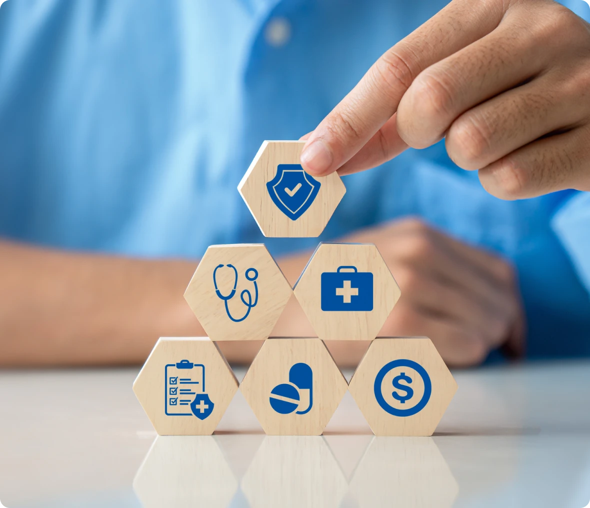 Person placing a wooden block with a medical icon on it, surrounded by other wooden blocks with icons on them