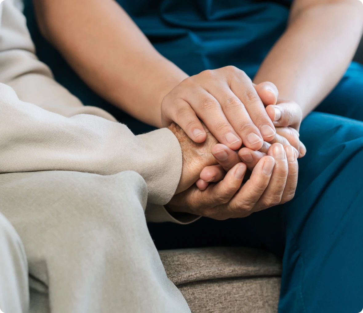 Nurse holding the hand of an woman, symbolizing the importance of providing care and support to those in need